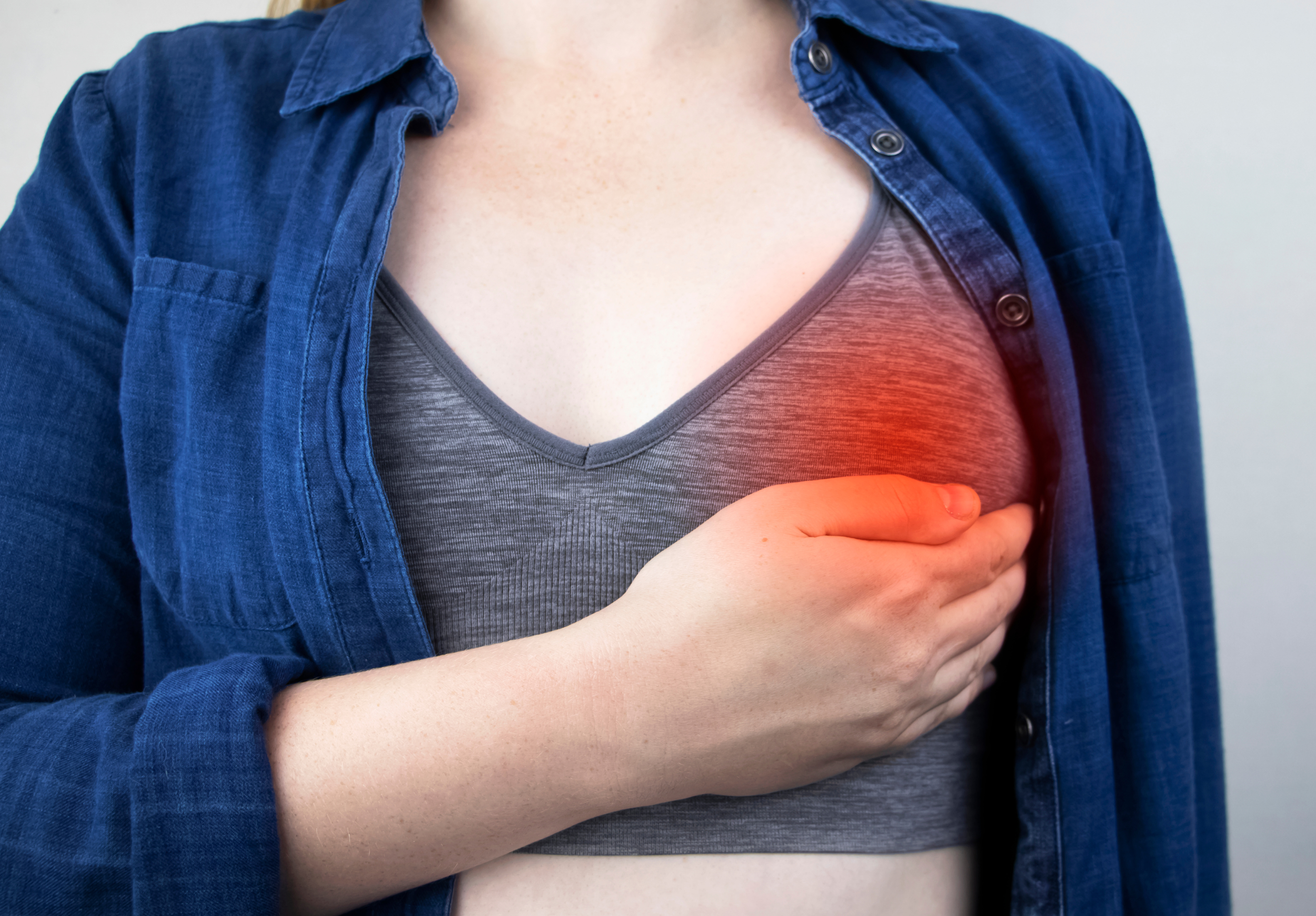 photo showing woman holding left breast with red pain mark 